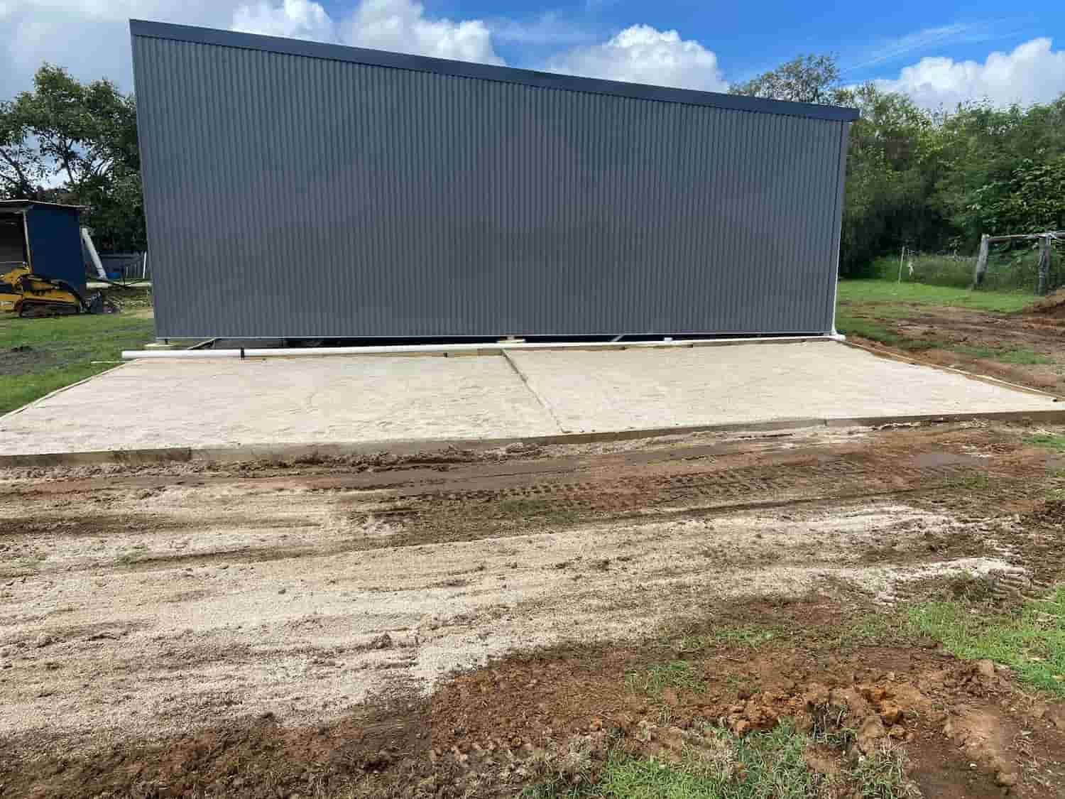 A Gray Metal Building is Sitting in the Middle of a Dirt Field — RCJJ Mini Loaders In Mareeba, QLD
