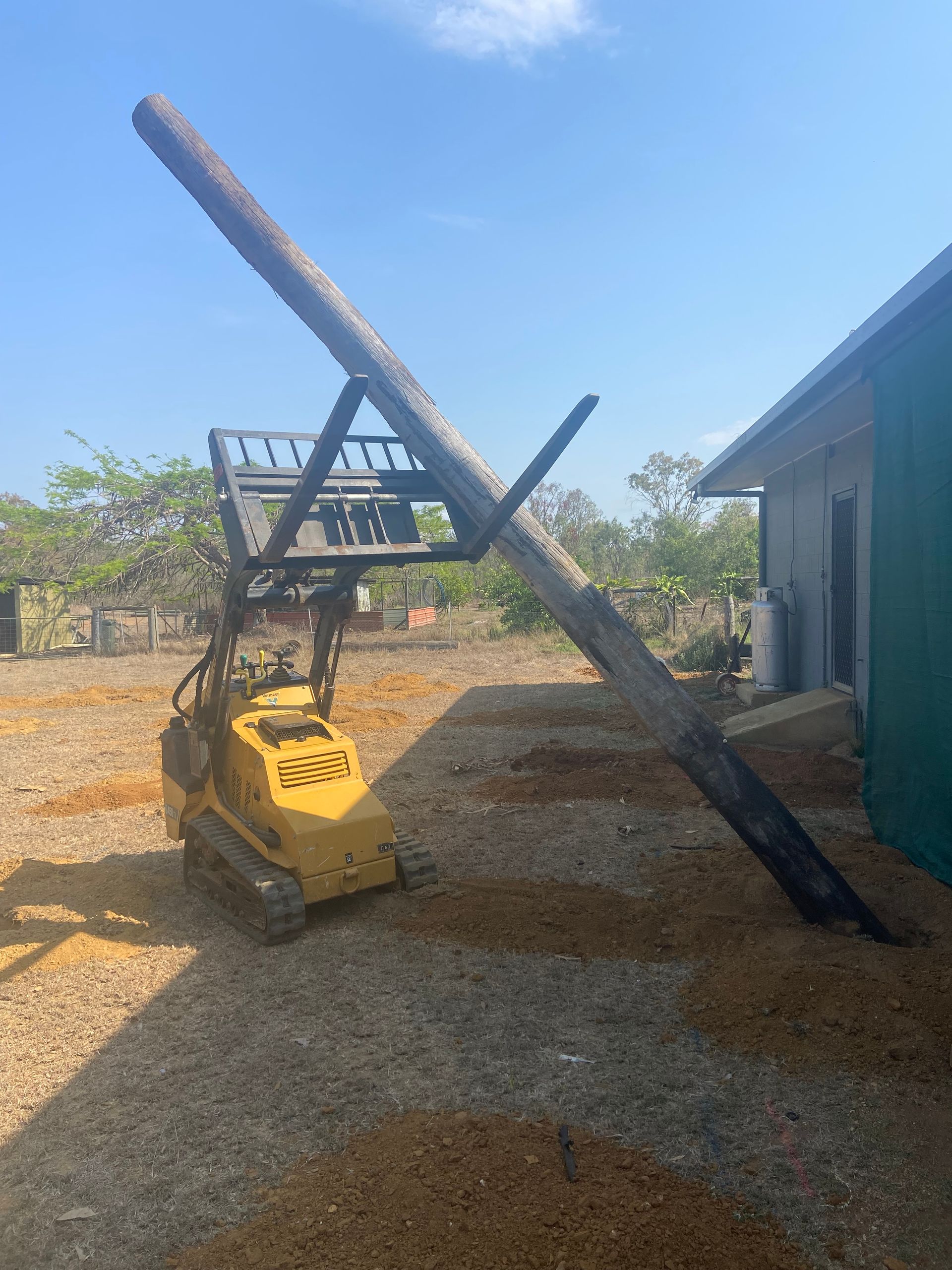 Mini Loader Lifting Tall Wood Pole — RCJJ Mini Loaders In Cairns, QLD