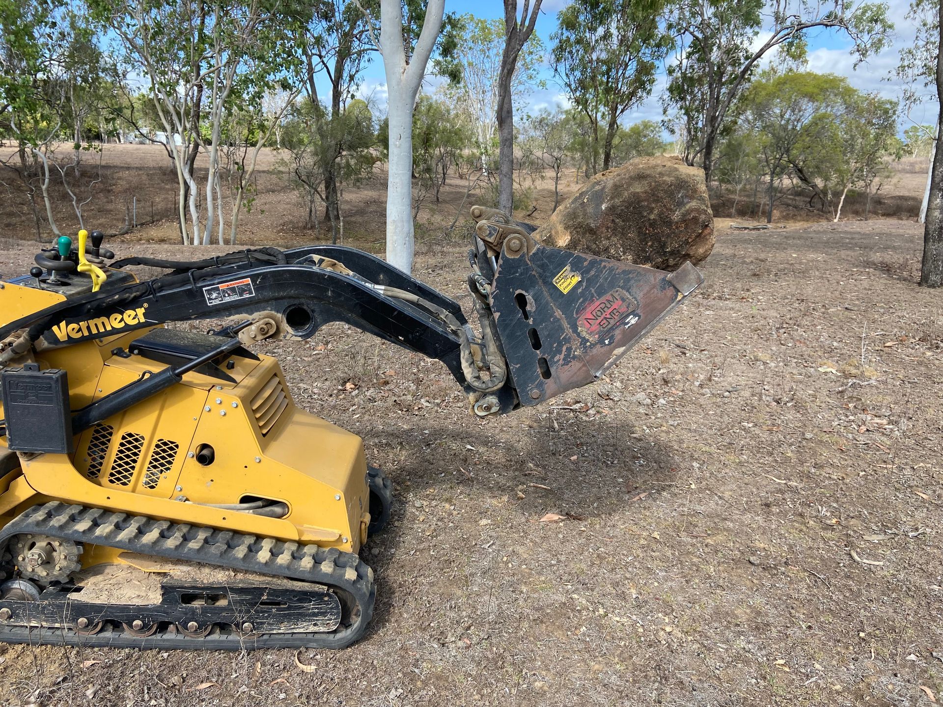 a Small Yellow Tractor is Scooping a Pile of Dirt in a Field — RCJJ Mini Loaders In Mareeba, QLD