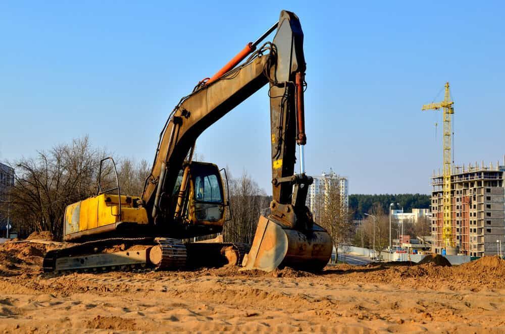 A Large Yellow Excavator is Sitting on Top of a Dirt Field — RCJJ Mini Loaders In Cairns, QLD