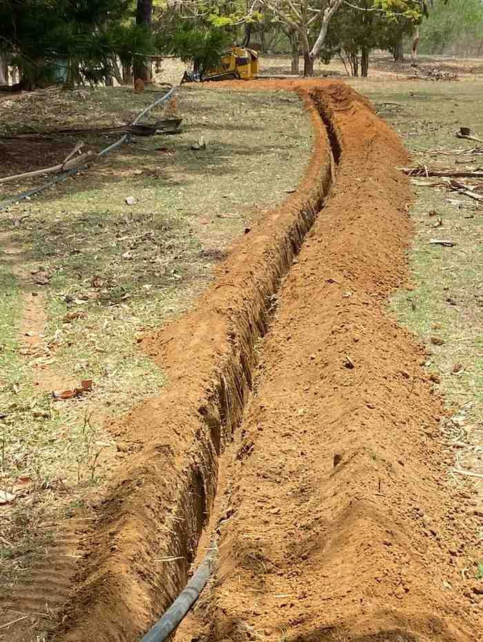 A Hose is Being Installed in the Dirt in a Field — RCJJ Mini Loaders In Tablelands, QLD