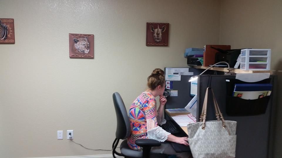 A woman is sitting at a desk talking on a cell phone