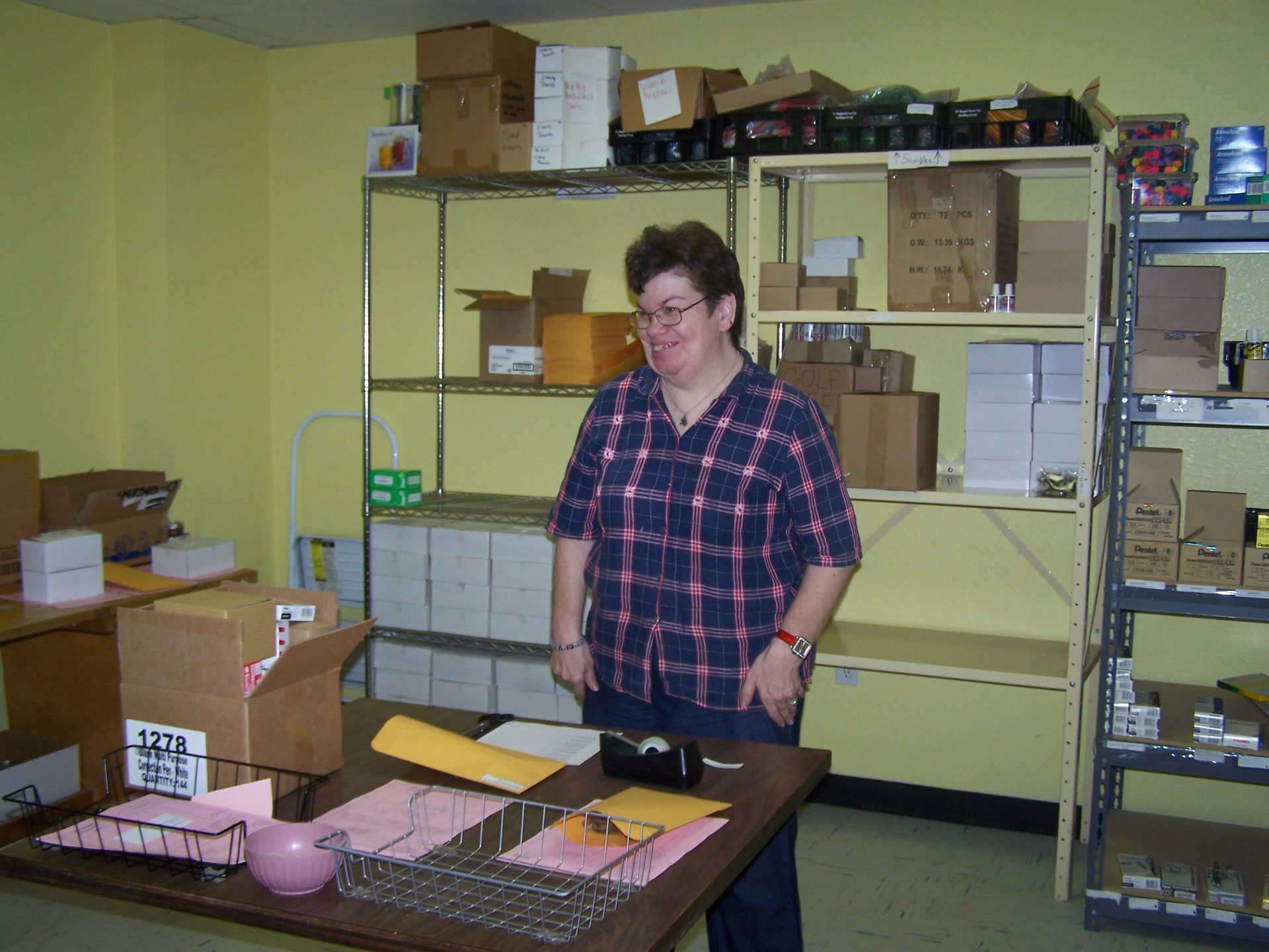 A woman in a plaid shirt is standing in a room full of boxes