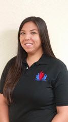 A woman is wearing a black polo shirt and smiling.