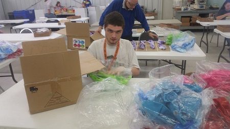 A man is sitting at a table with boxes and plastic bags.