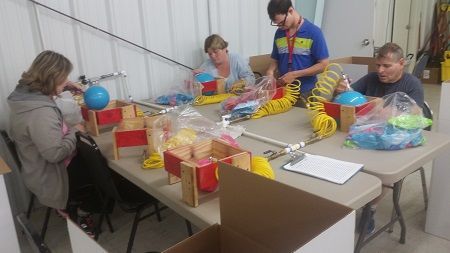 A group of people are sitting at a table working on toys.