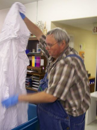 A man in a plaid shirt is holding a white cloth