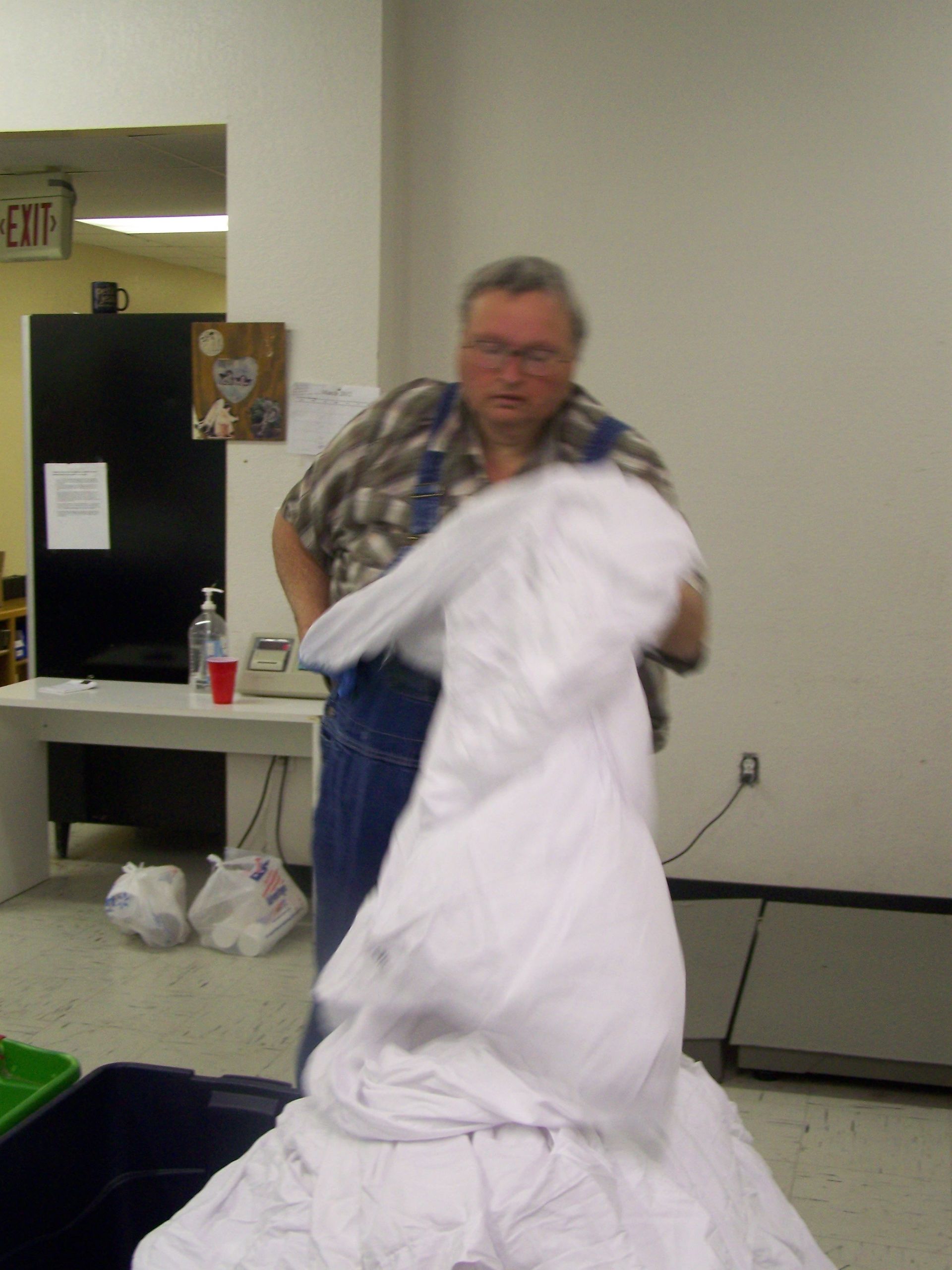 A man holding a pile of white sheets in front of an exit sign