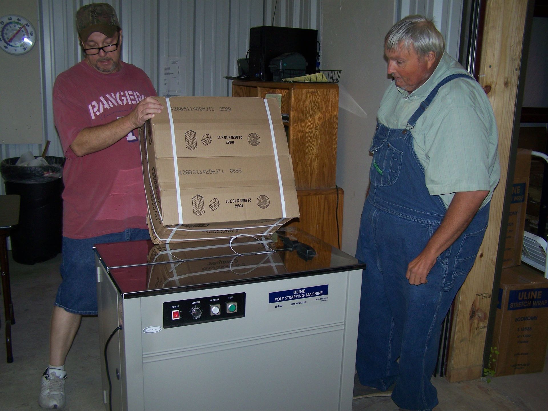 A man in a rangers shirt is holding a cardboard box
