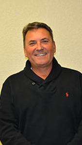 A man in a black sweater is smiling for the camera.