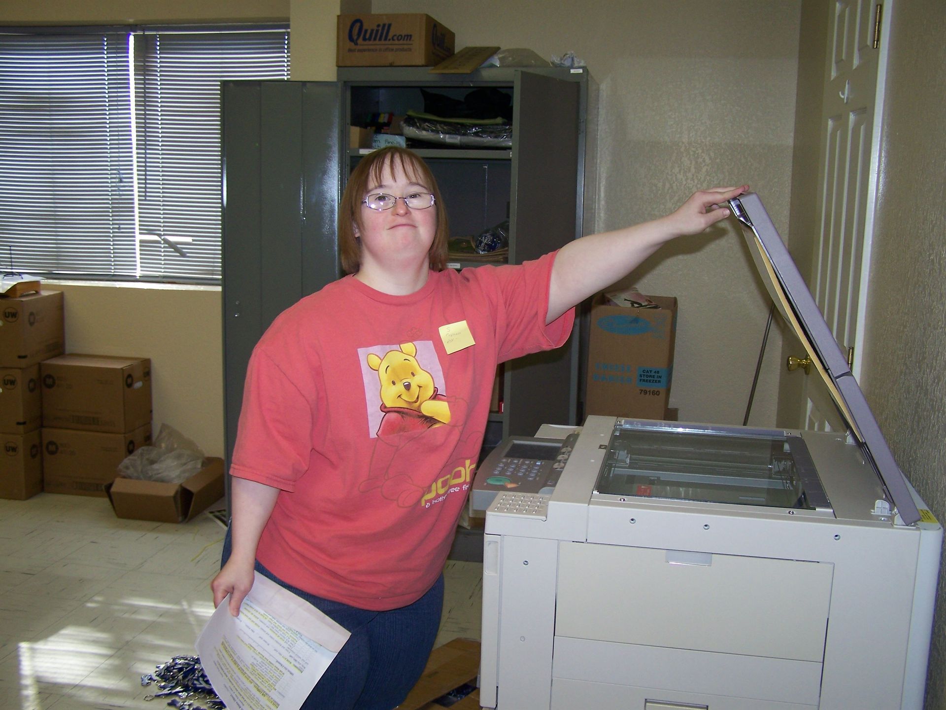 A woman in a winnie the pooh shirt is standing in front of a printer