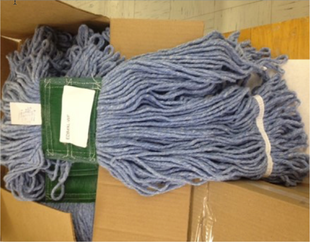 Blue mop heads are stacked on top of each other in a cardboard box