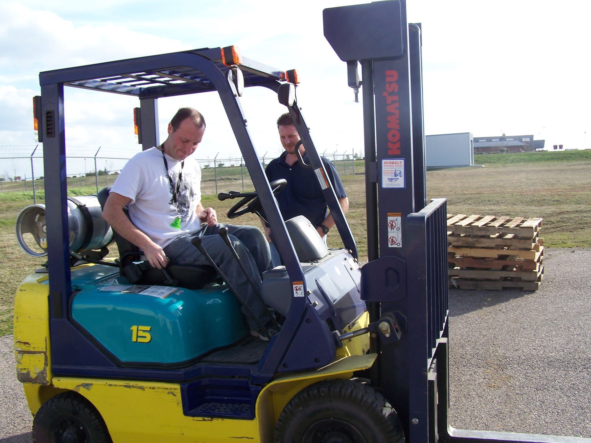 Two men are sitting in a komatsu forklift