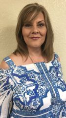 A woman in a blue and white dress is smiling for the camera.