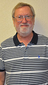 A man with a beard and glasses is wearing a striped shirt.