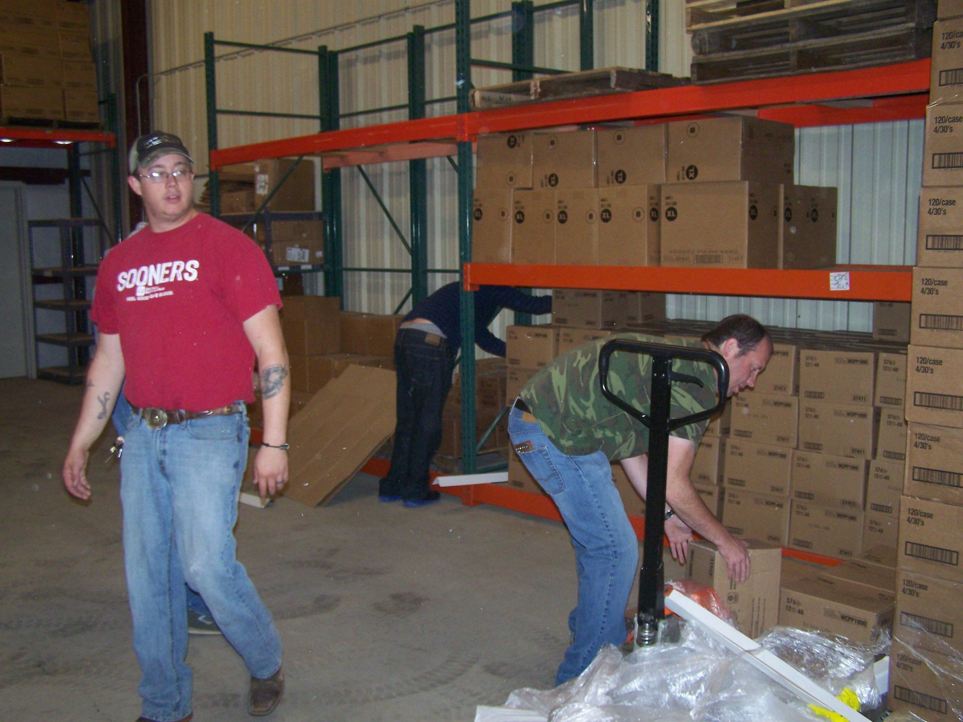 Two men in a warehouse one wearing an oklahoma shirt
