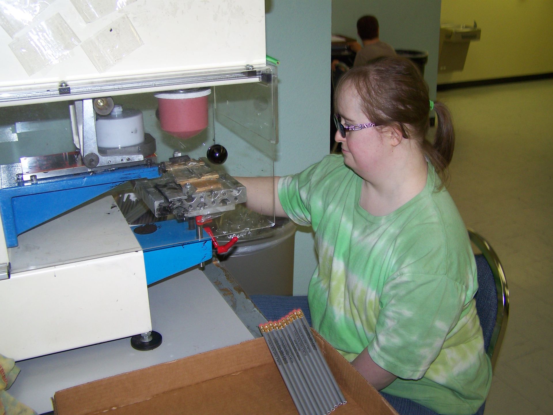 A woman in a green shirt is working on a machine