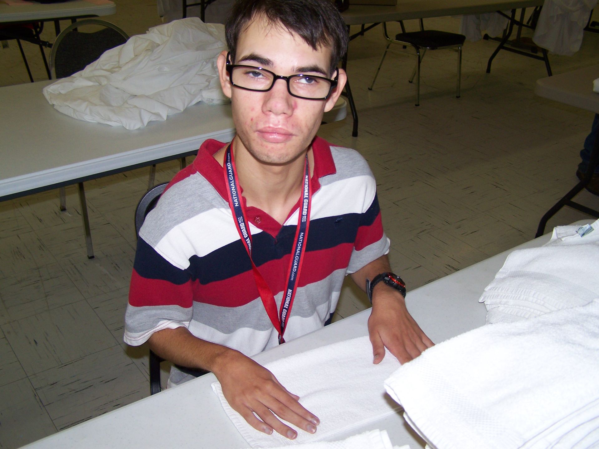 A young man wearing glasses is sitting at a table