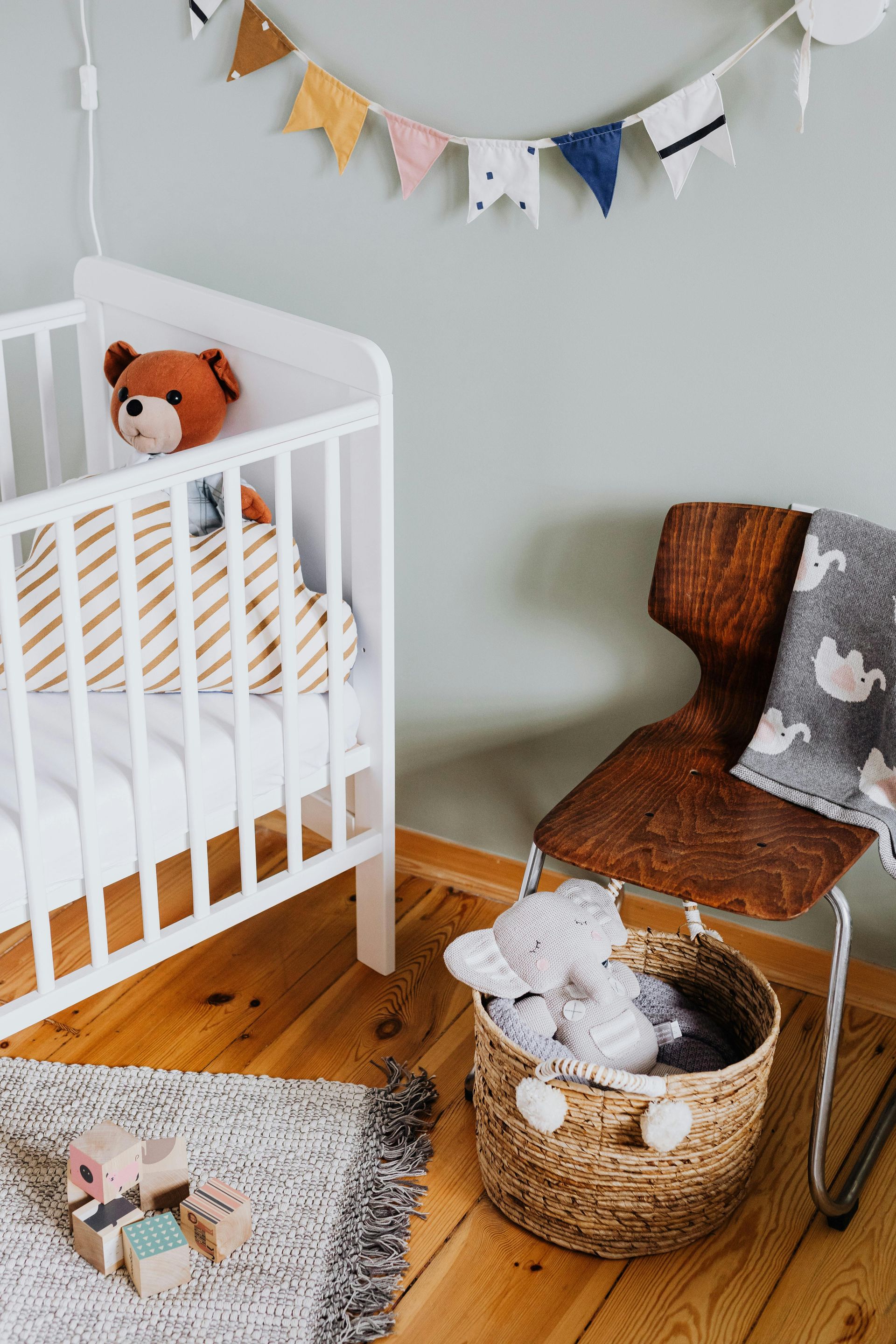 A baby room with a crib , chair , basket and toys.