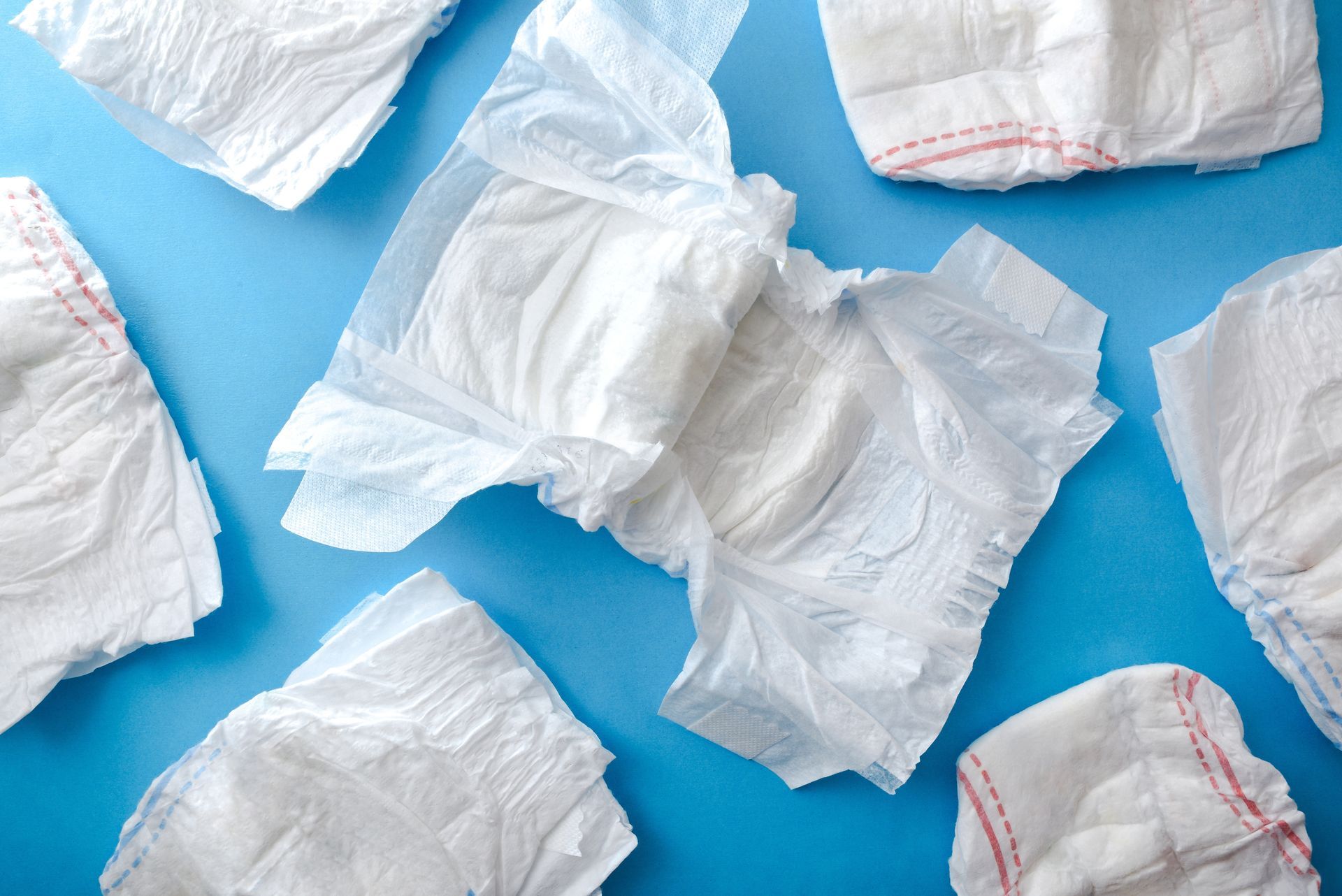 A bunch of diapers are laying on top of each other on a blue surface.