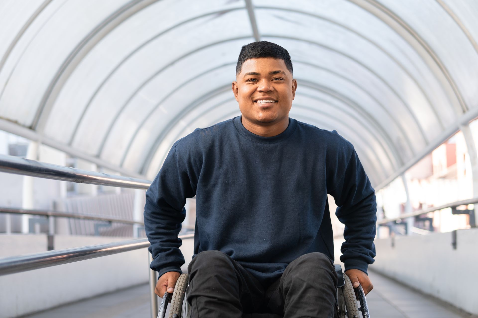 A man in a wheelchair is smiling and looking at the camera.