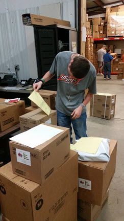 A man is standing in a warehouse looking at a piece of paper.