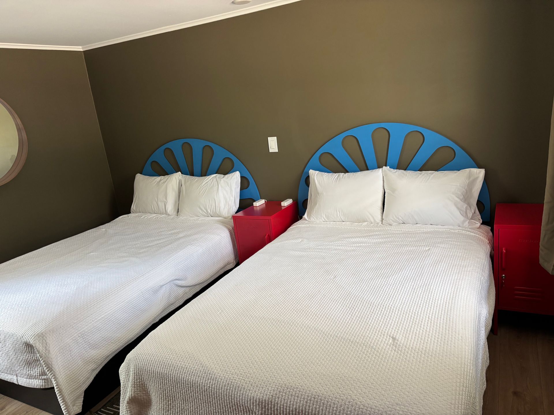 Two twin beds with white bedding and blue headboards in a simple hotel room