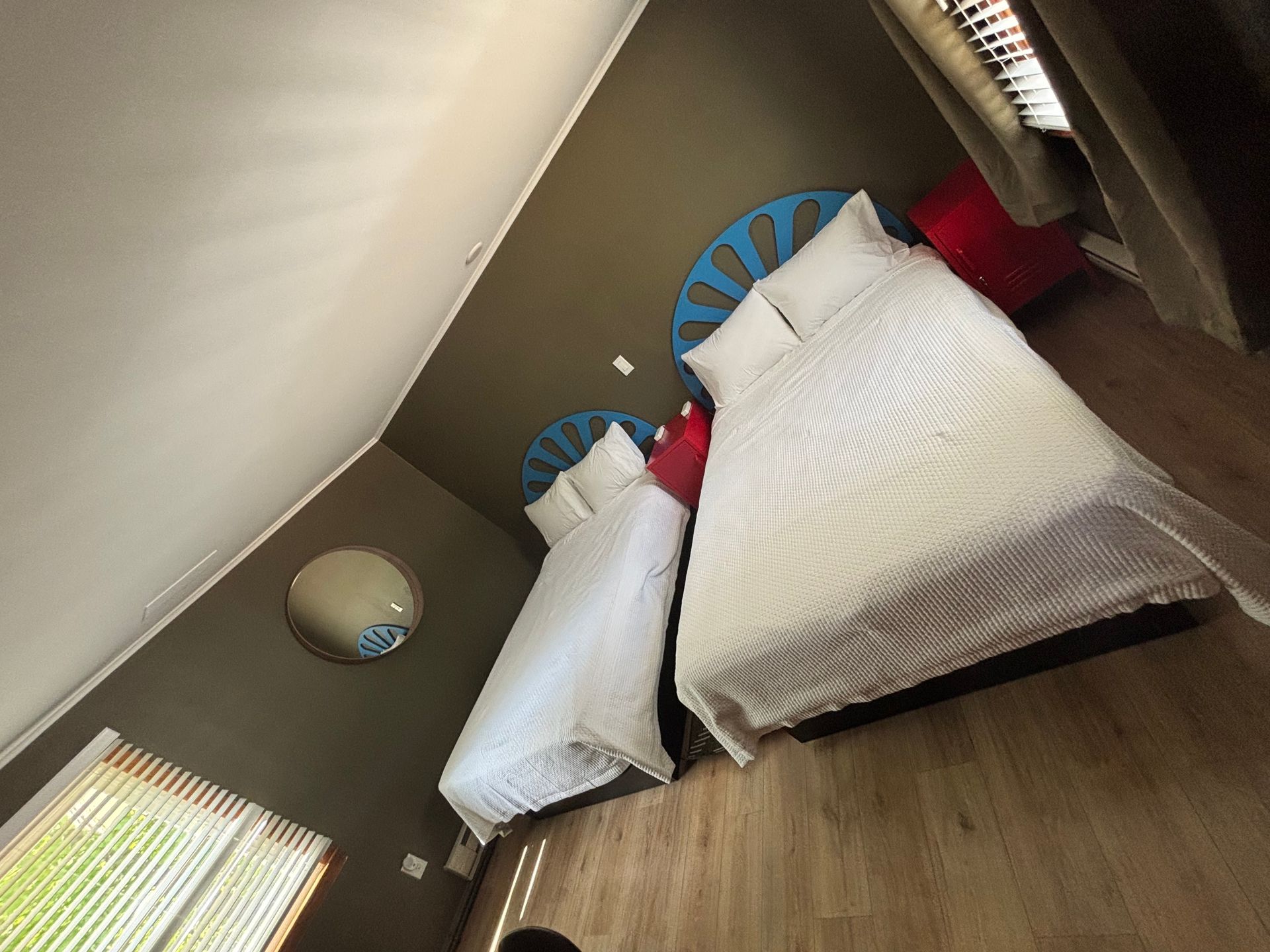 Small bedroom with two single beds, white bedding, and a wooden floor, viewed at an angle.