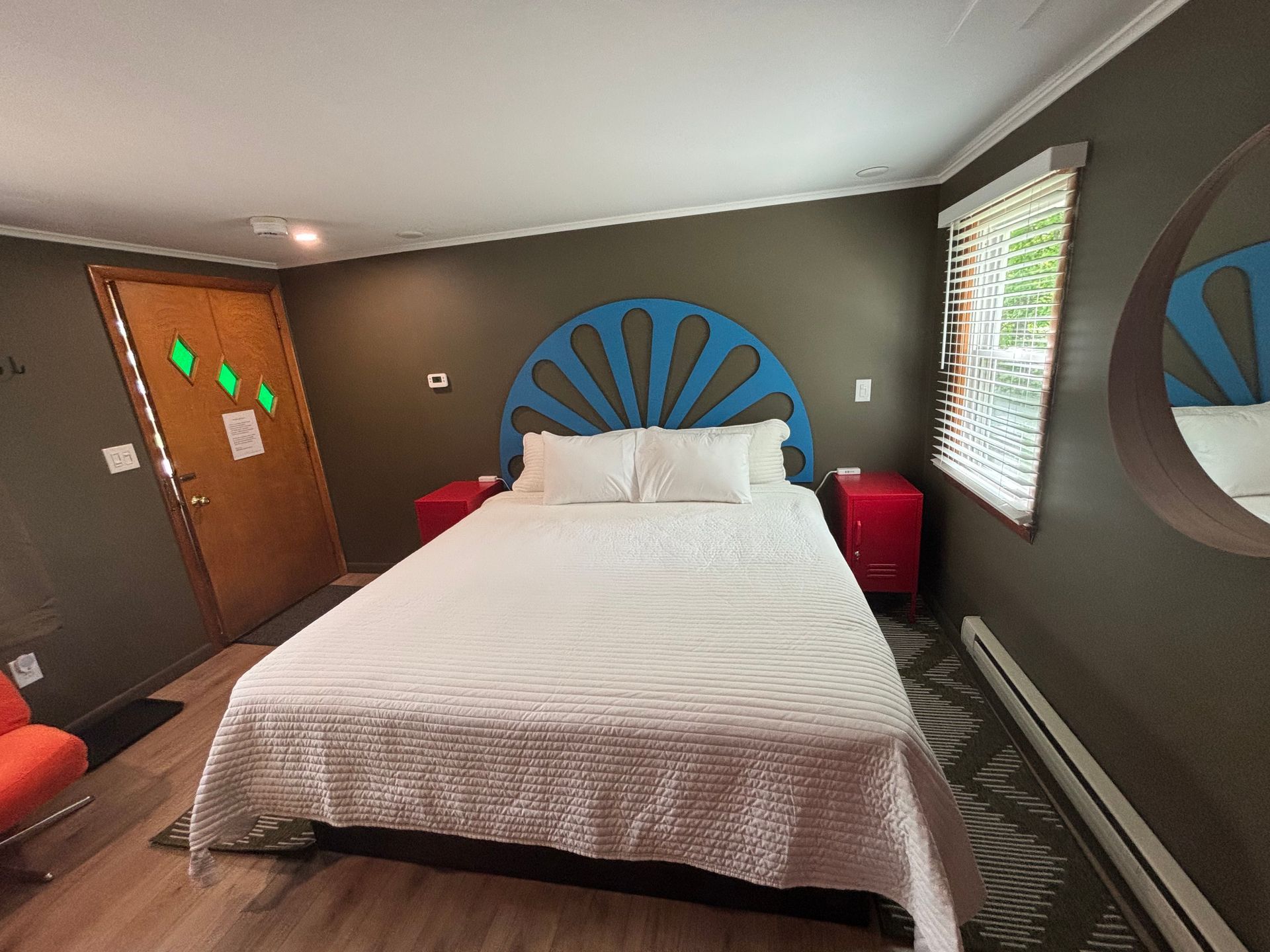 Bedroom with a white bed, blue fan-shaped headboard, brown walls, and window blinds.