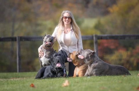 Rachel with a group of her dogs in a field .
