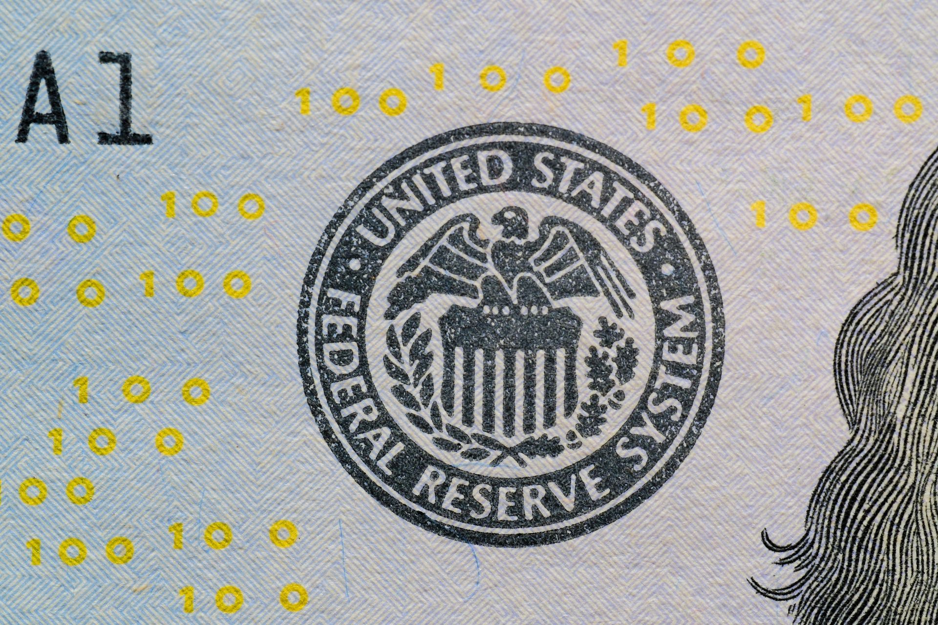 Close-up of a $100 bill, showing the Federal Reserve seal with an eagle and text 