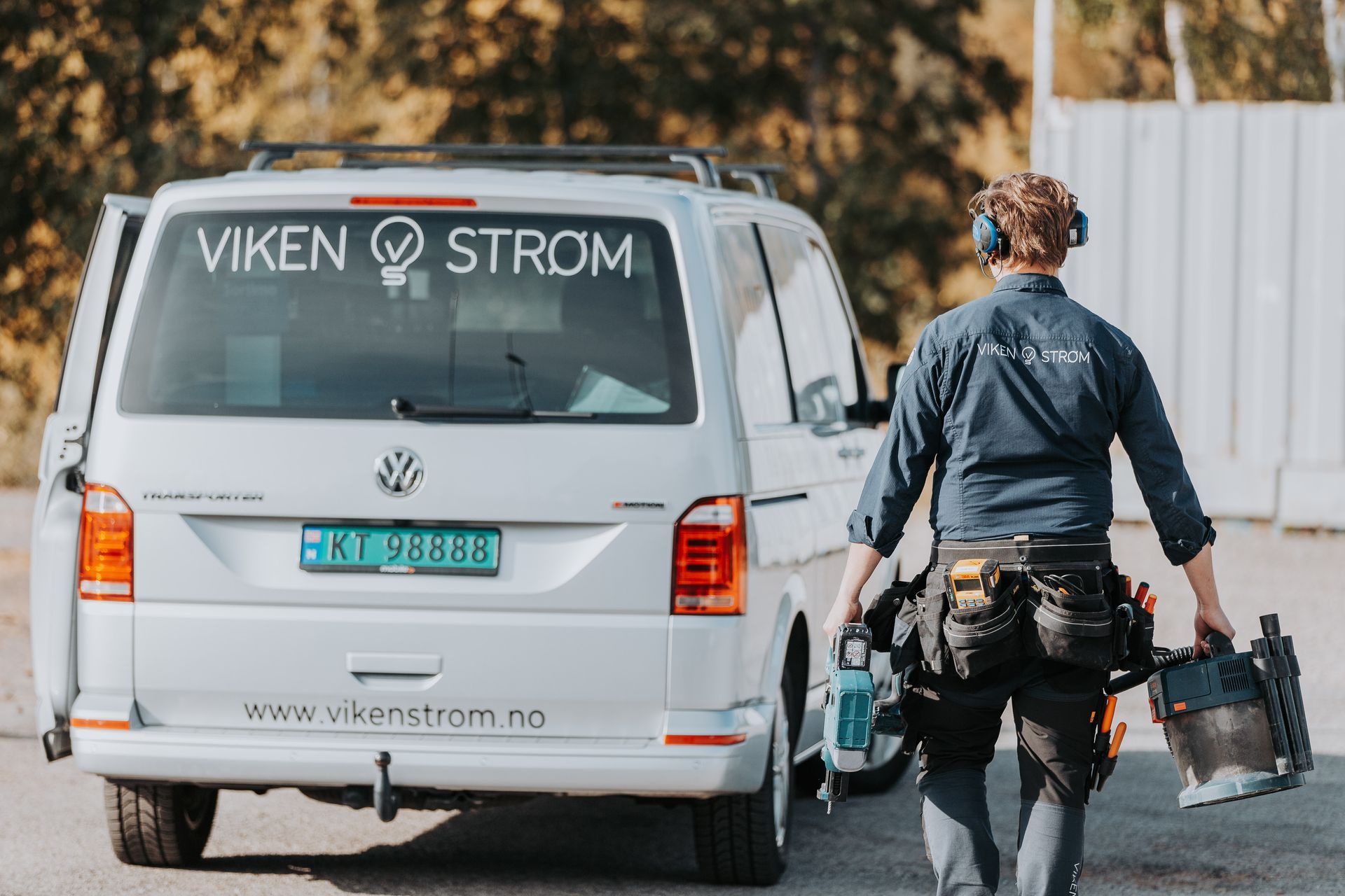 Elektriker bærer utstyr ut i bil etter endt oppdrag