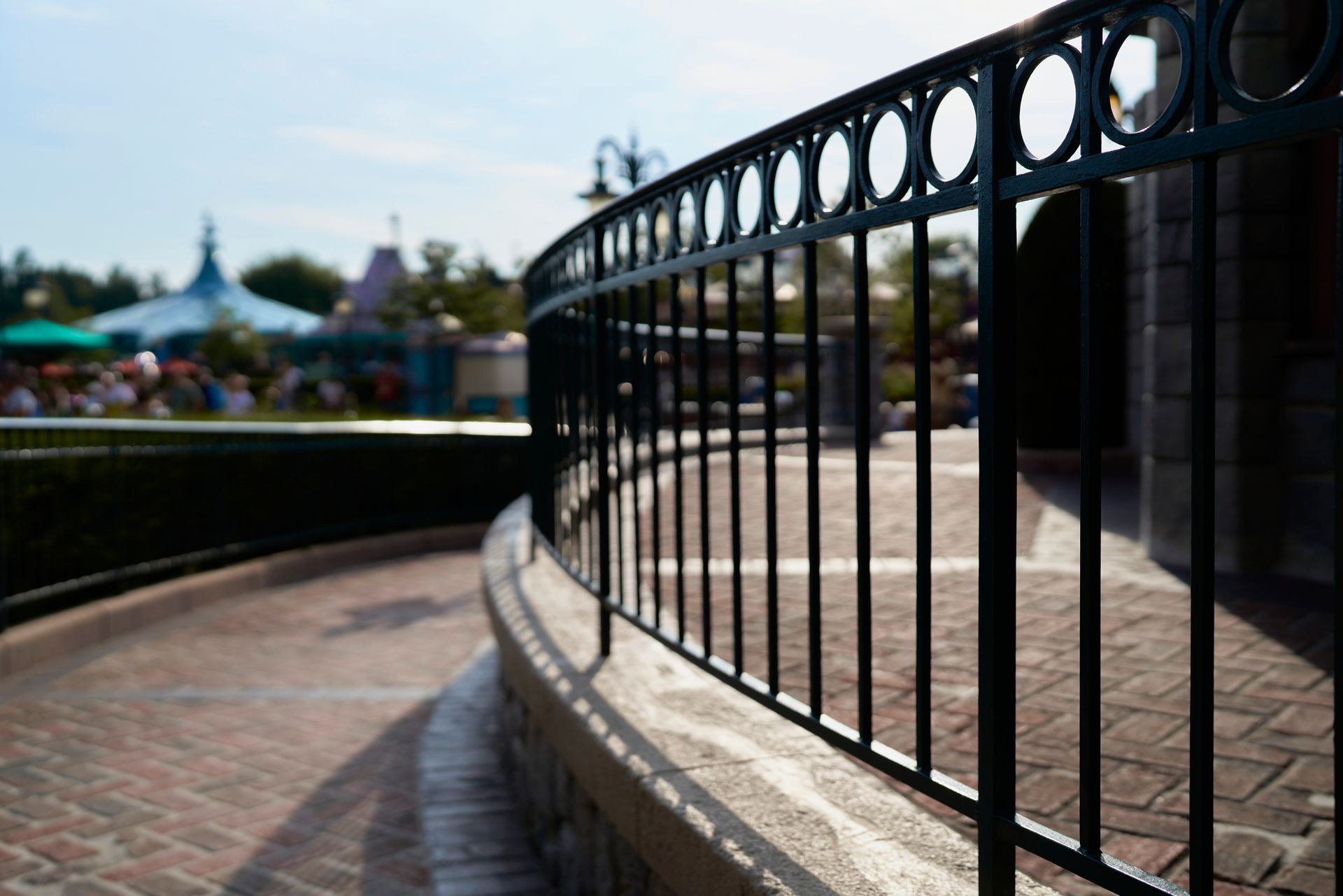 A close up of a wrought iron fence on a brick walkway.