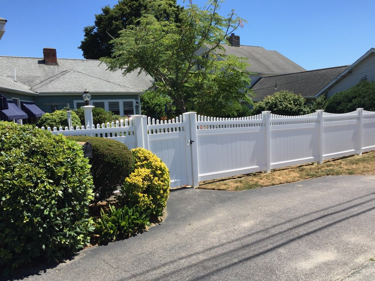 A white fence with a gate in front of a house