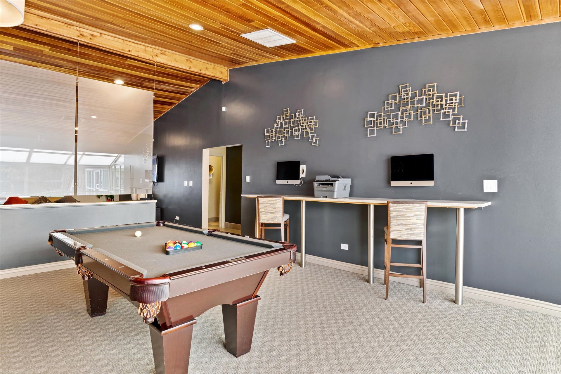 Pool table and work area in a room with wood ceiling and gray walls.