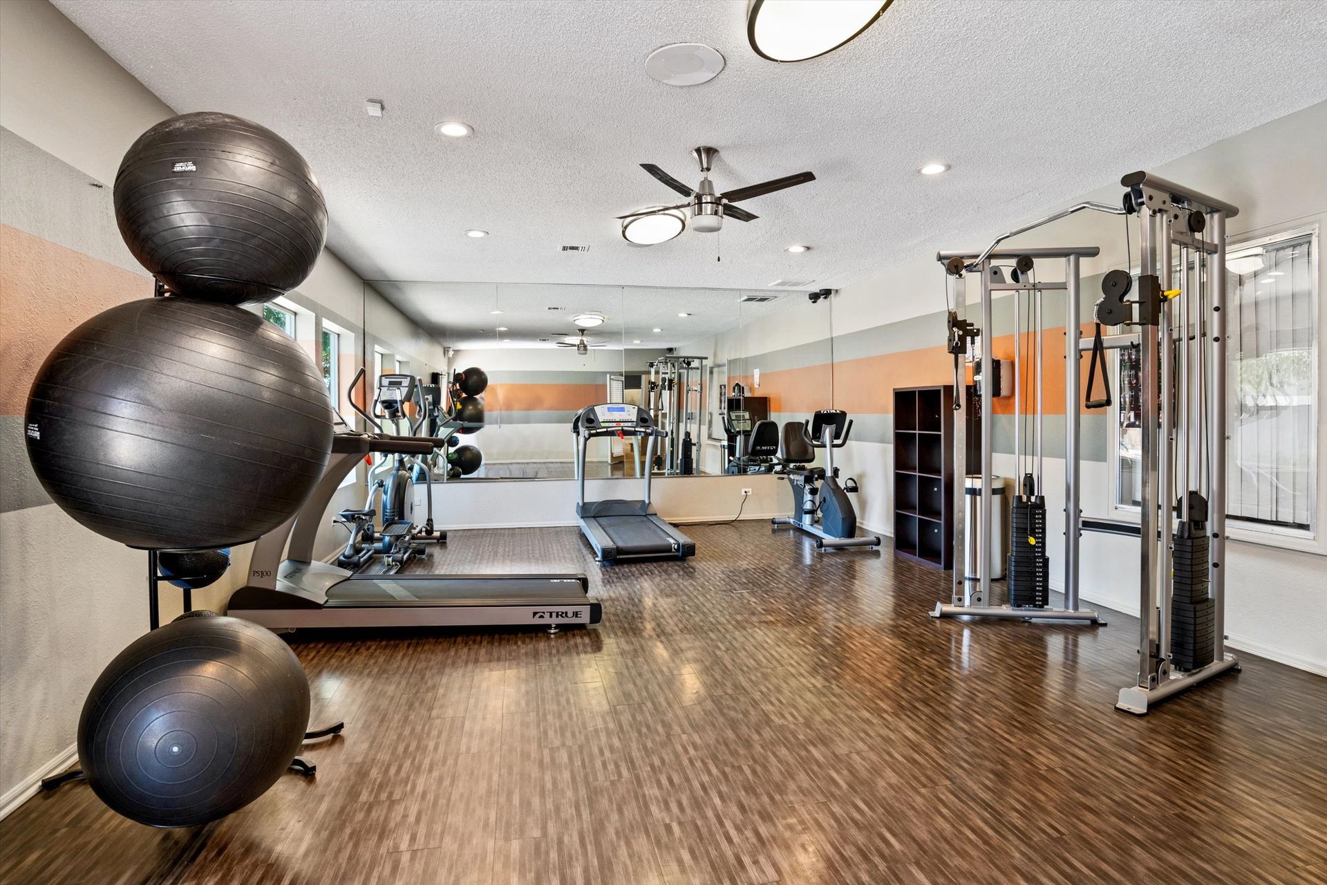Gym with exercise equipment, including treadmills, weight machine, and exercise balls.