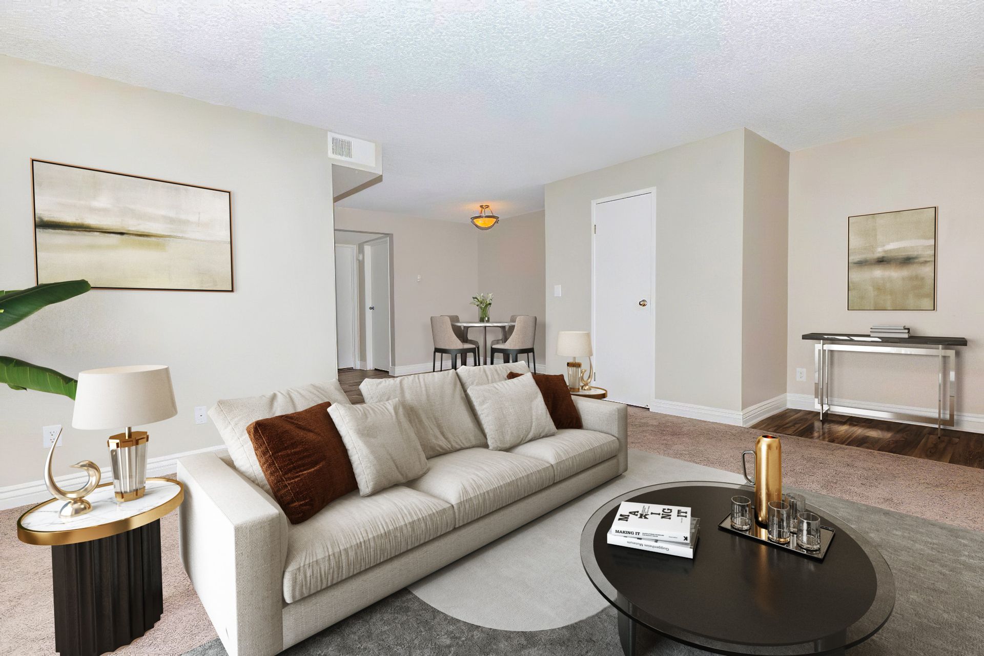 Living room with sofa, coffee table, and side tables; neutral tones, artwork, dining area visible.