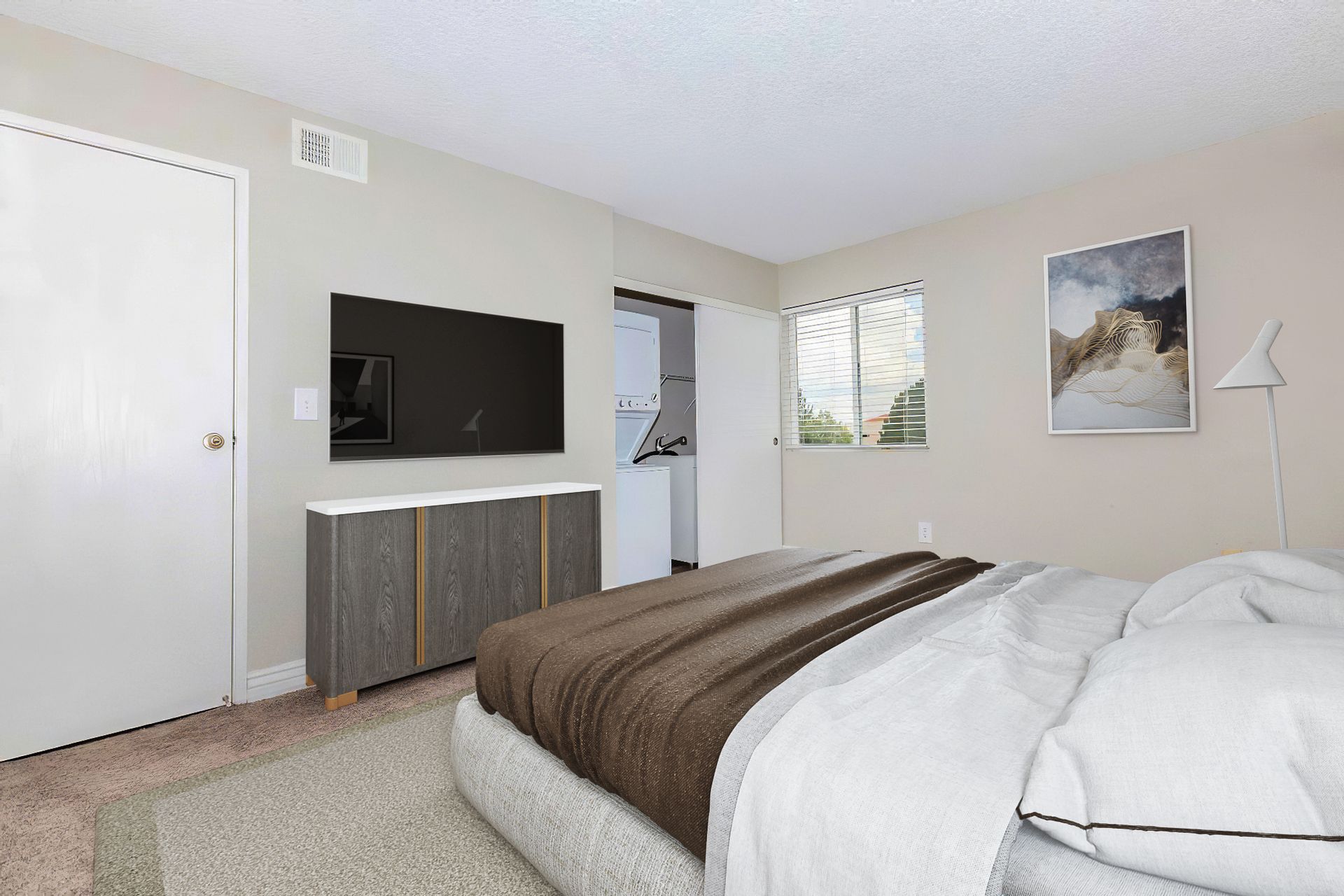 Bedroom with a bed, TV, and cabinet against light-colored walls. Window and art on the wall.