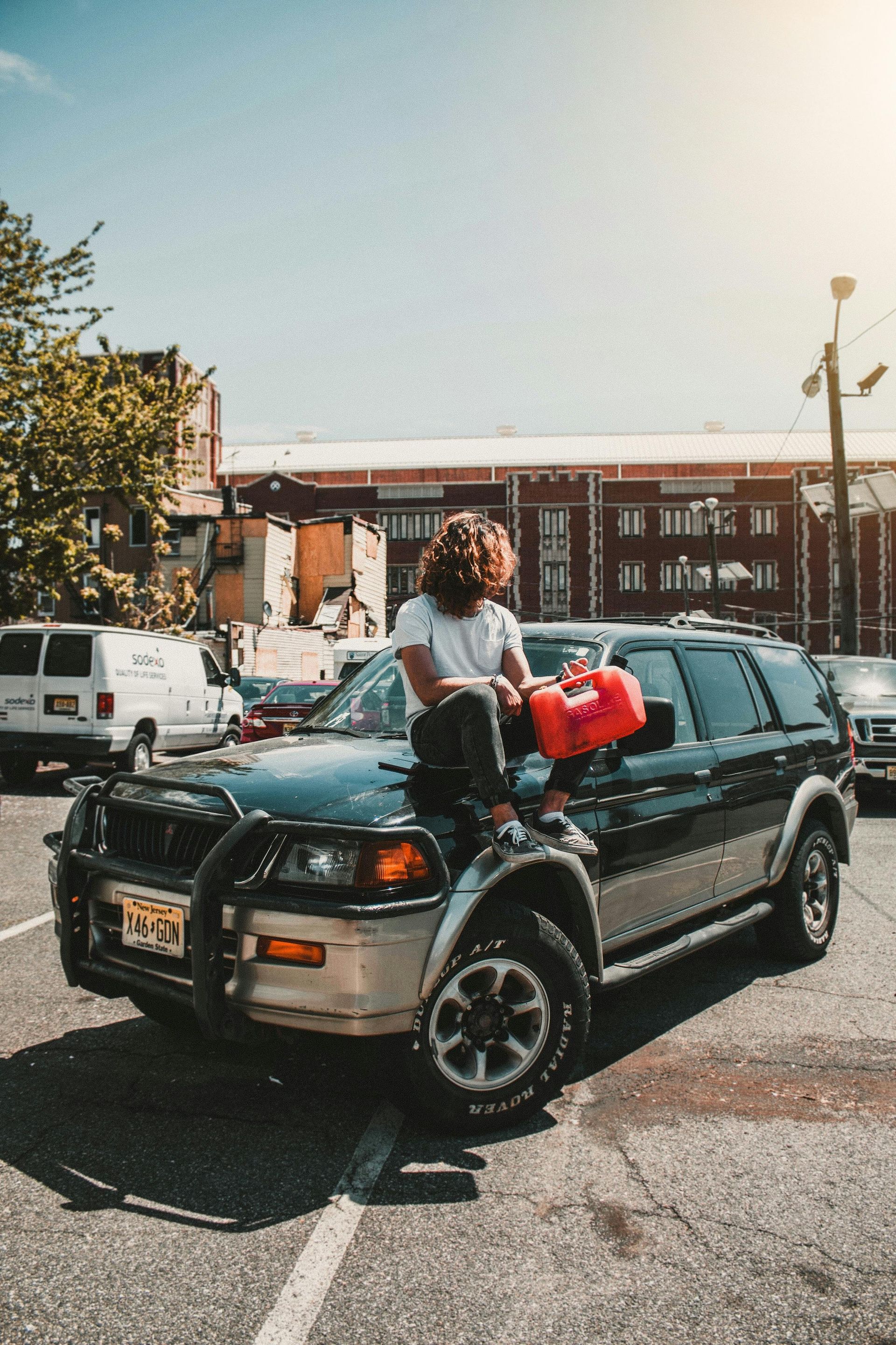 A man is holding a red gas can next to a car.