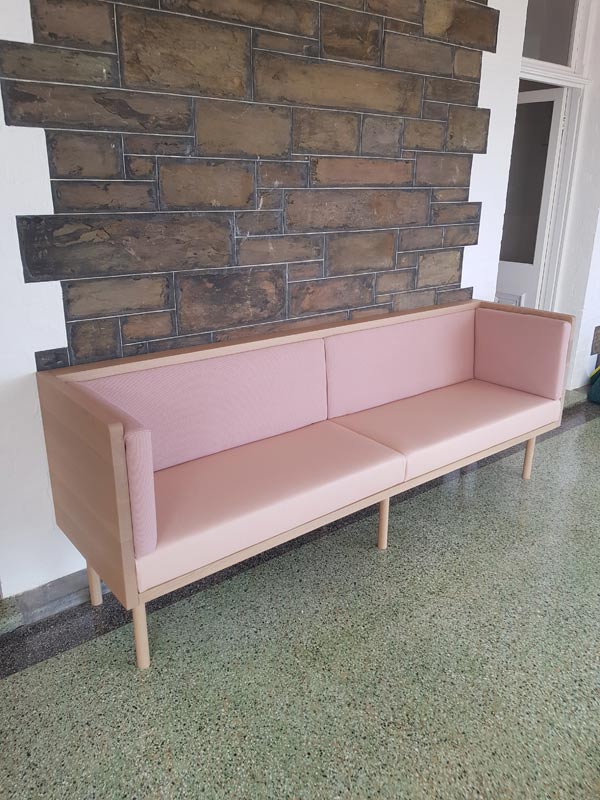 pink couch in front of stone wall