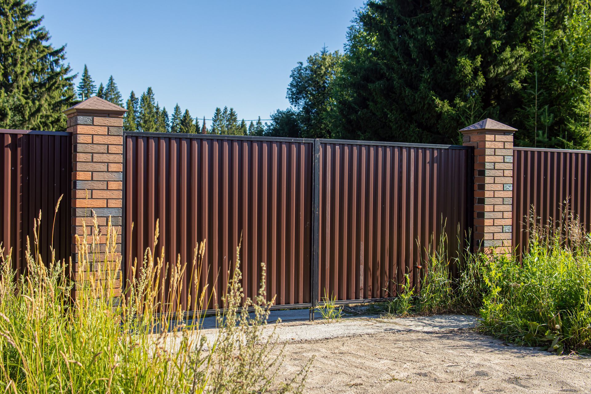 White vinyl fence with gate, set against a green lawn and blue sky.