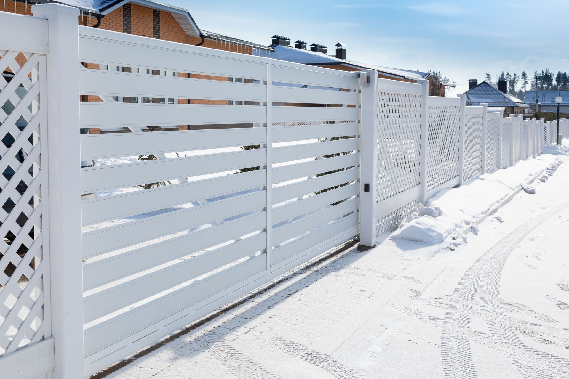 White horizontal-slat fence with a lattice section in a snowy environment.