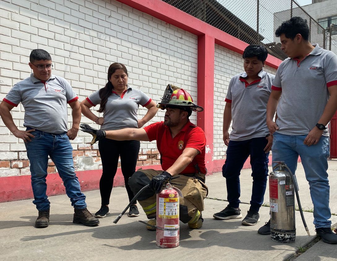 Bombero demuestra el uso del extintor de incendios a un grupo de personas afuera.