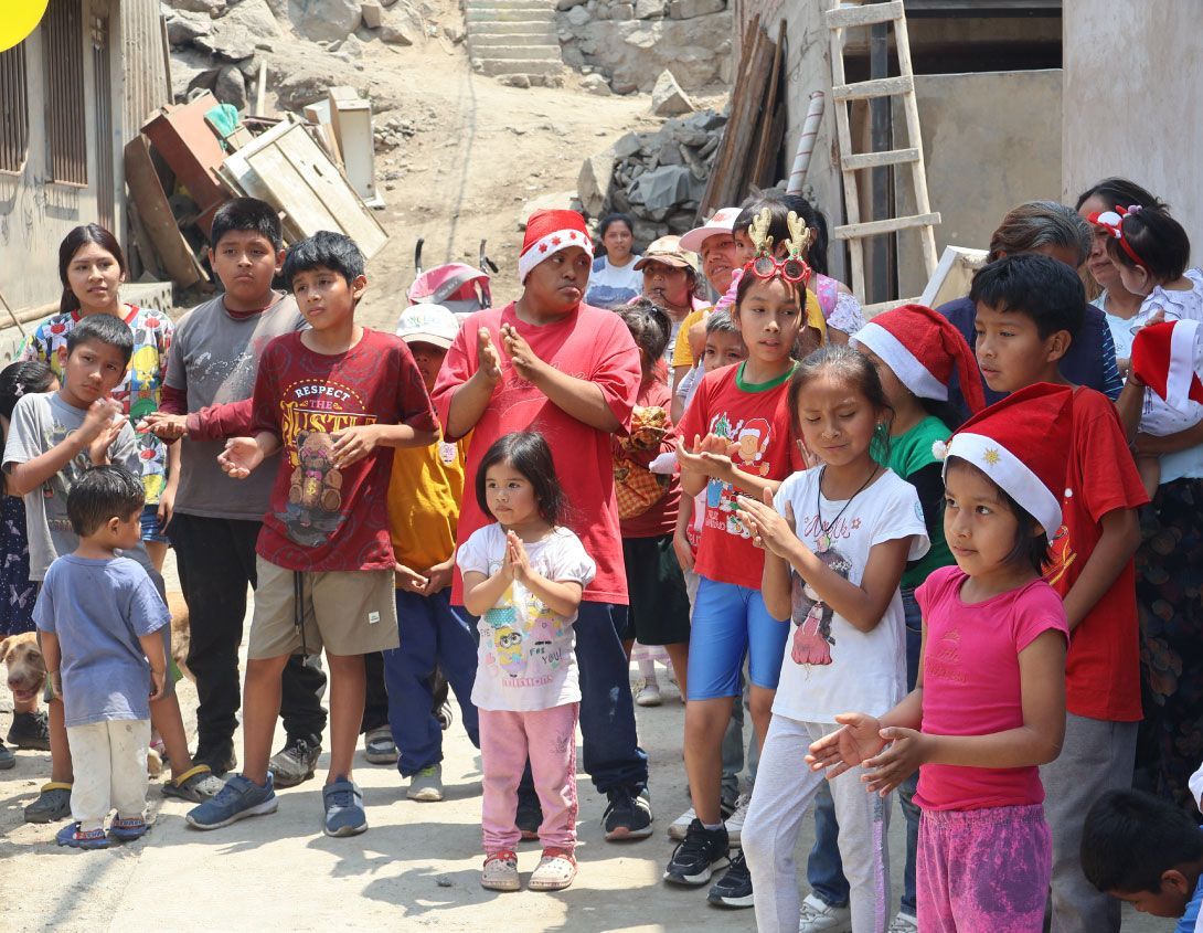 Niños y adultos con gorros de Papá Noel aplaudiendo al aire libre.