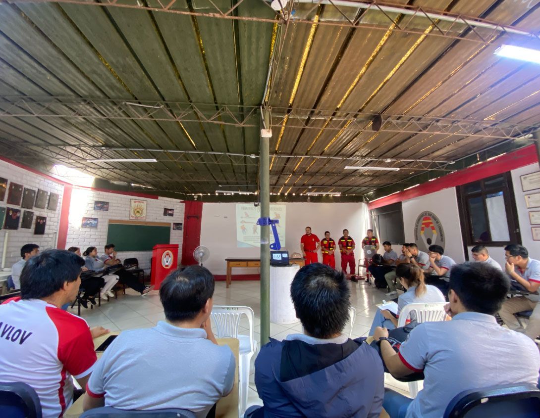 Personas que asisten a una reunión en un amplio espacio interior. 