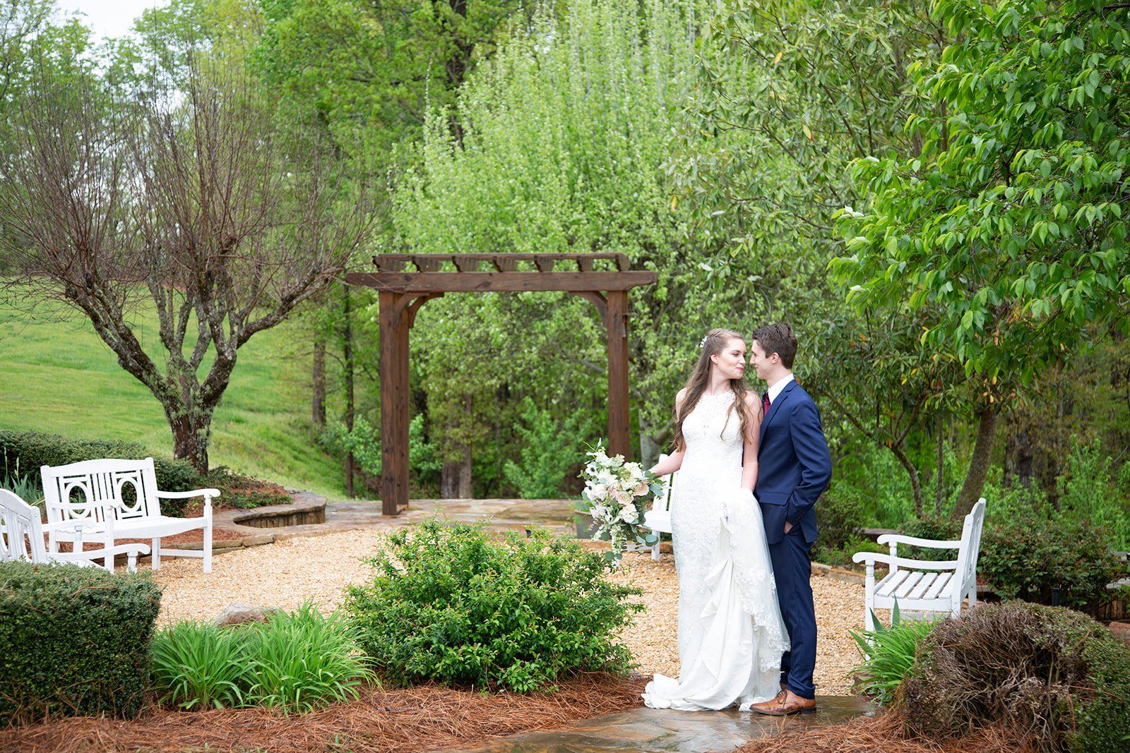 A bride and groom are standing next to each other in a garden.