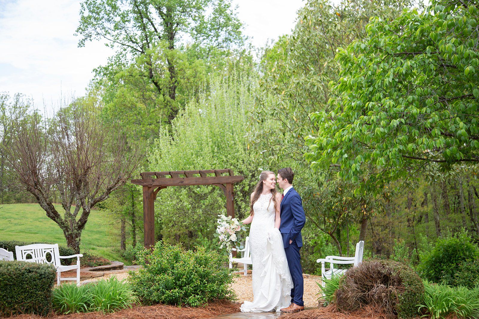 A bride and groom are kissing in a garden.