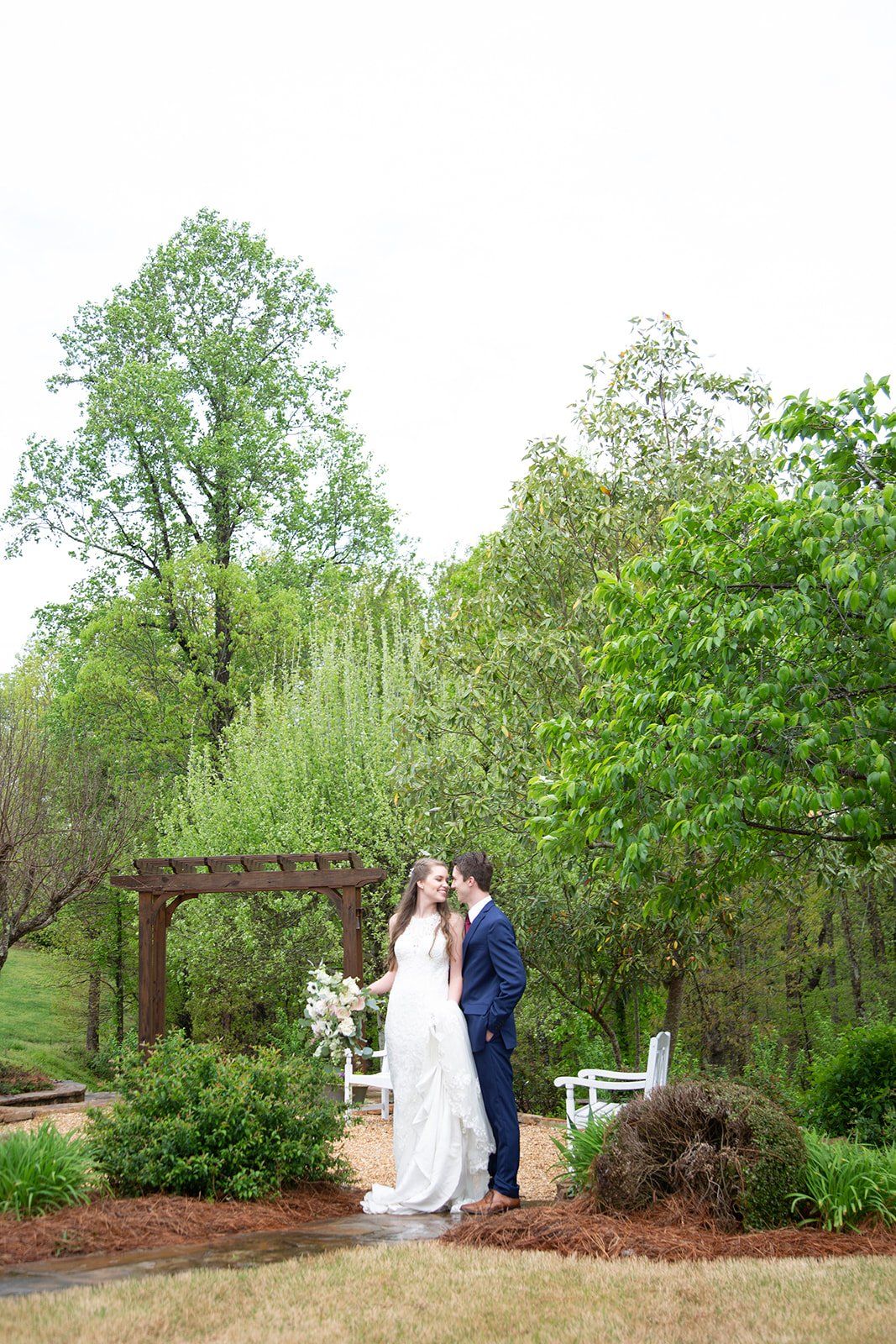 A bride and groom are kissing in a garden.