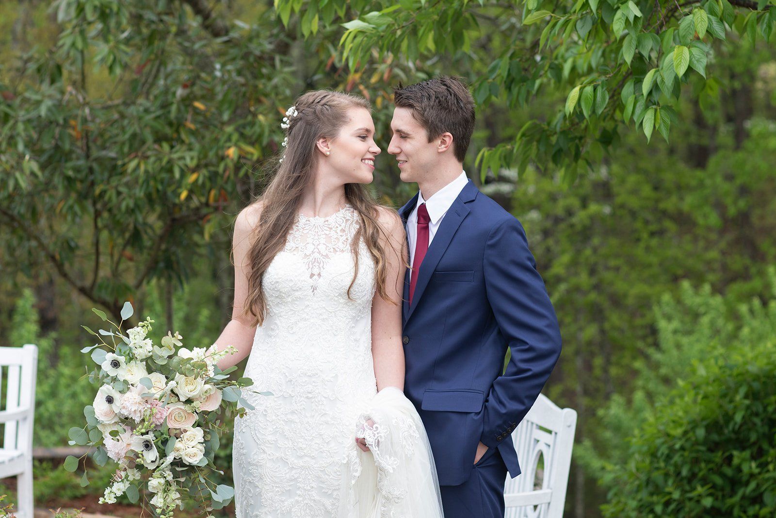 A bride and groom are standing next to each other and looking at each other.
