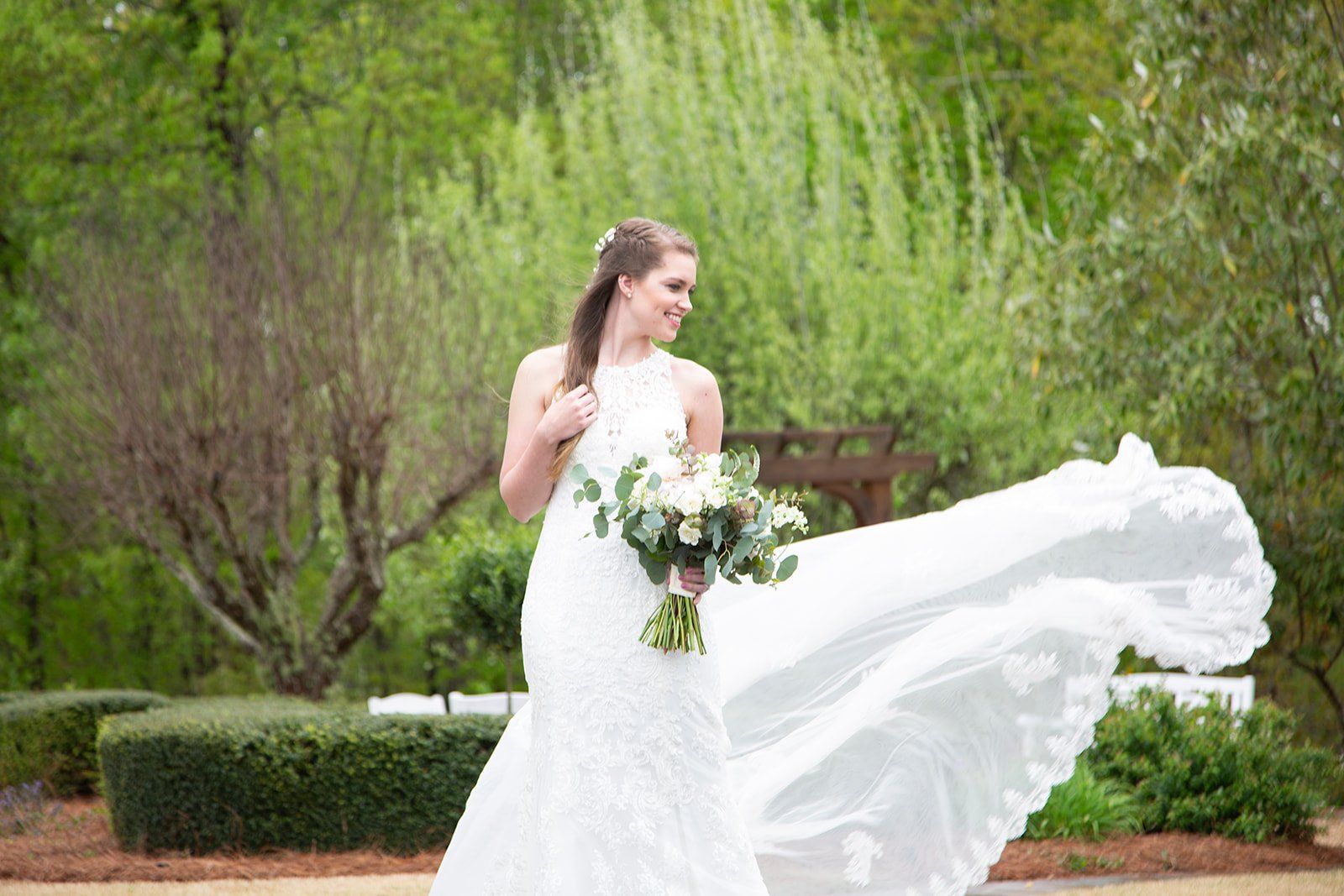 A bride in a wedding dress is holding a bouquet of flowers and her dress is blowing in the wind.